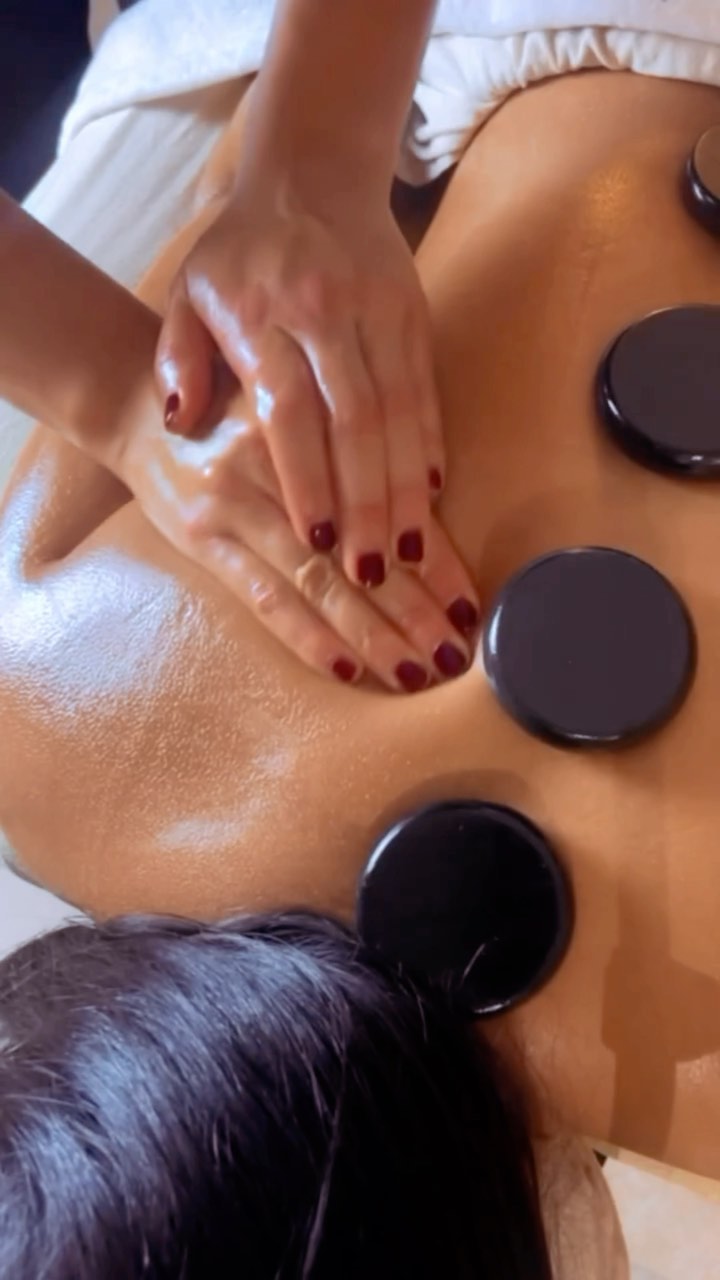 Masaje con piedras calientes en Beauty Specialist: piedras volcánicas a lo largo de la espalda y manos trabajando el hombro